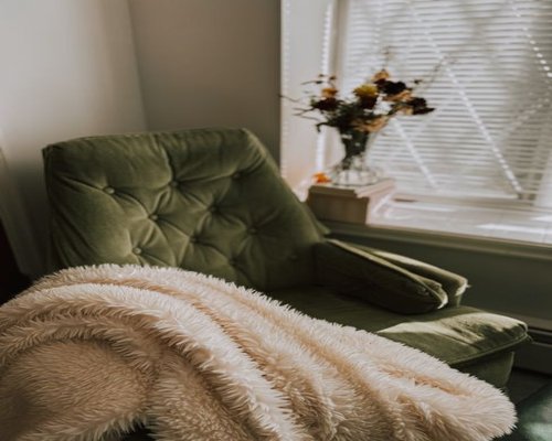 A cozy reading corner by a window with soft natural sunlight filtering through
